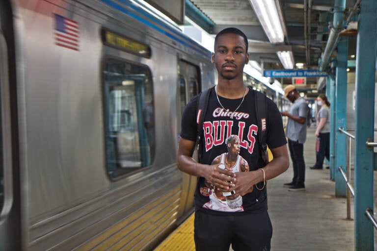 Elijah Brown stands next to a Market-Frankford line train inside Girard Station