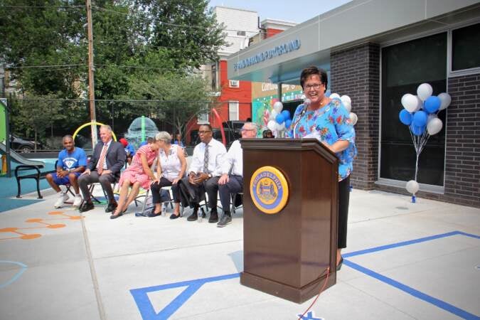 Kathryn Ott Lovell speaks from a podium at a playground