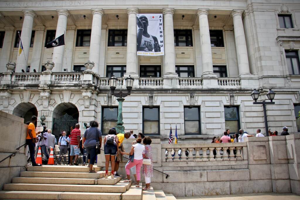A banner celebrating Olympic track star Athing Mu hands on the front of Trenton City Hall.