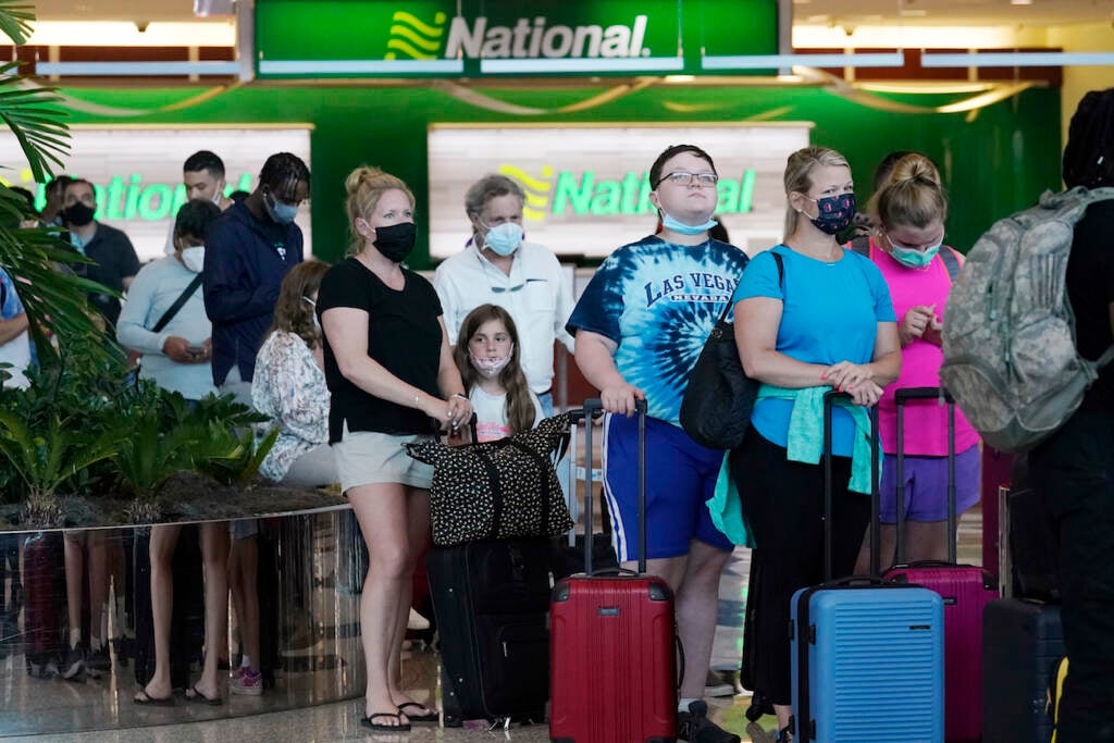 People wait in line to rent vehicles at Miami International Airport