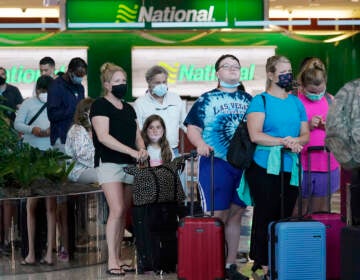 People wait in line to rent vehicles at Miami International Airport