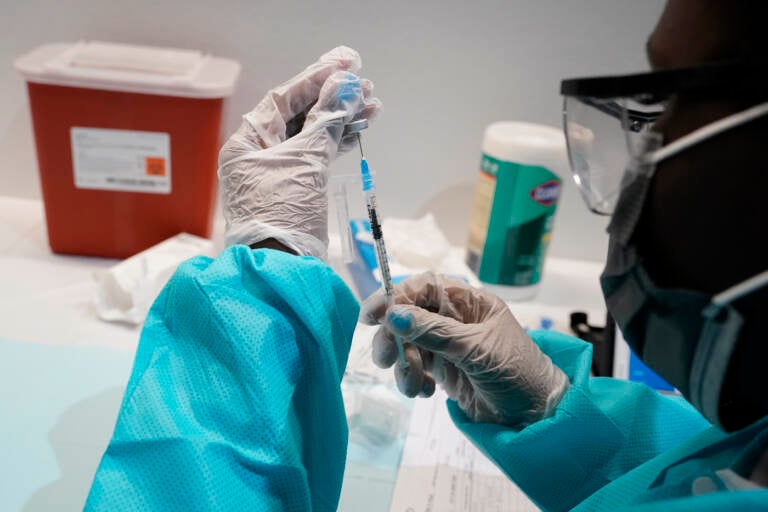 A health care worker fills a syringe with the Pfizer COVID-19 vaccine