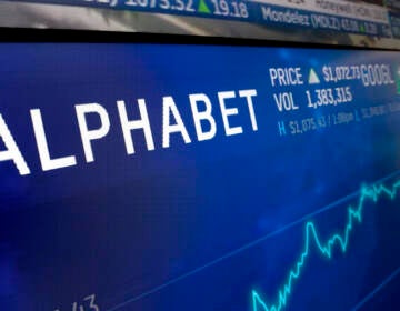 FILE- In this Feb. 14, 2018, file photo the logo for Alphabet appears on a screen at the Nasdaq MarketSite in New York. S&P Dow Jones Indices is shuffling the line-up of three of the 11 groups that make up the benchmark S&P 500 index. On Monday, 20 companies in the index including famous names like Facebook, Alphabet and Netflix will find a new home. (AP Photo/Richard Drew, File)