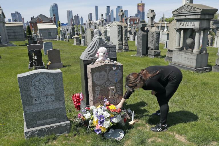 Sharon Rivera adjusts flowers and other items left at the grave of her daughter, Victoria