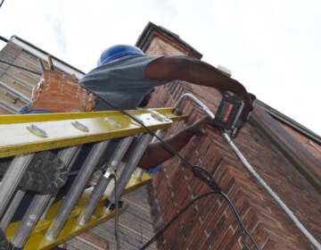 A worker replaces a main electrical service line on a home