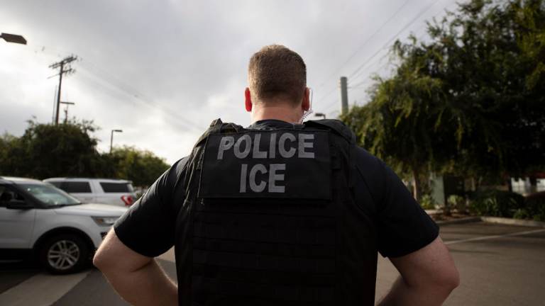 An Immigration and Customs Enforcement officer is seen from behind.