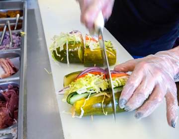 A chef cutting a pickle sandwich at Elsie's Pickles