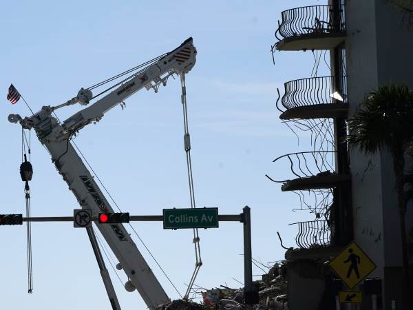 An American flag flies from a crane on July 4th next to the Champlain Towers South condo building