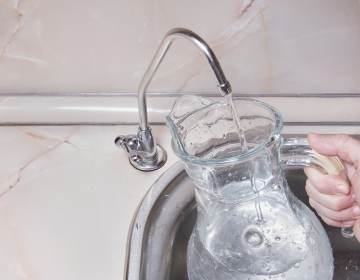 A person fills up a jug of water from a faucet.