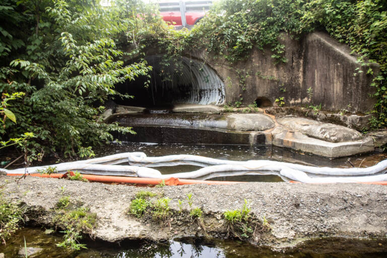 An oil spill cleanup sock in a small waterway leading to Chester Creek