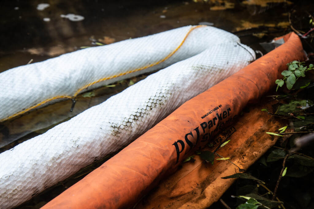 An oil spill cleanup sock in a small waterway leading to Chester Creek