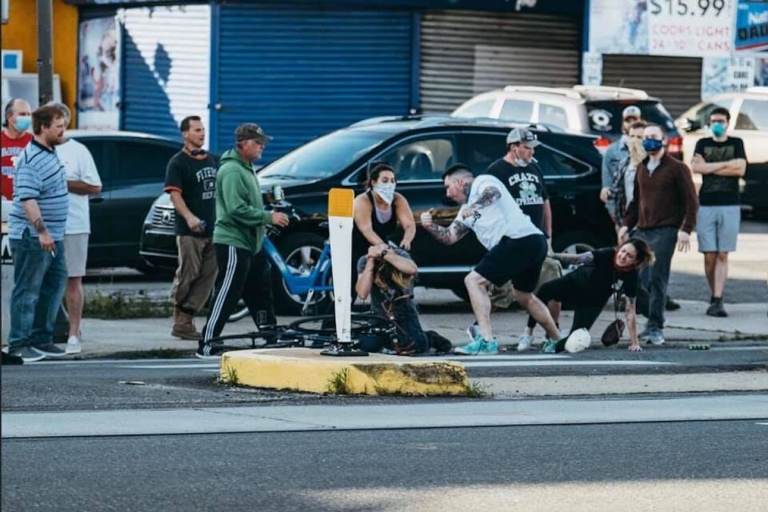 A group of people attack a man who has been knocked off his bike