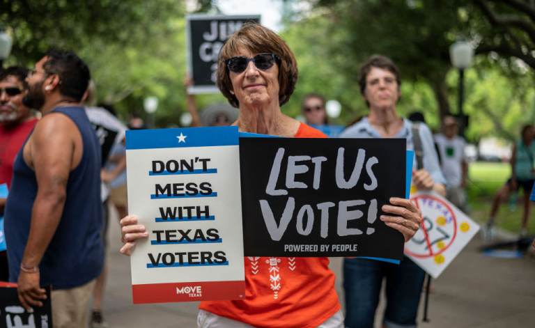 A woman holds signs at a rally at the state Capitol on June 20 in Austin, Texas, to fight SB7, a controversial voting bill. (Sergio Flores/Getty Images)