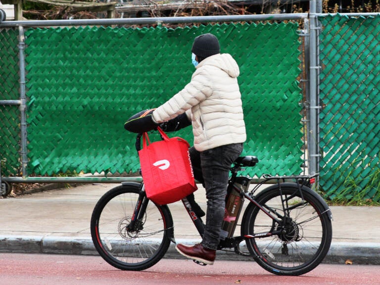A DoorDash delivery person rides their bike