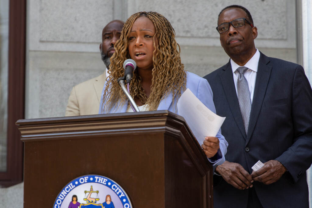 Jamie Gauthier speaks from a podium, with other elected officials behind her