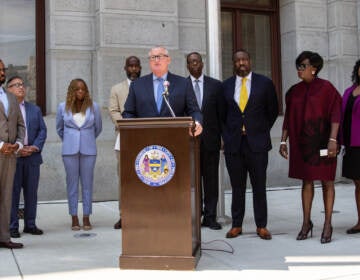 Jim Kenney speaks from a podium, with other elected officials behind him