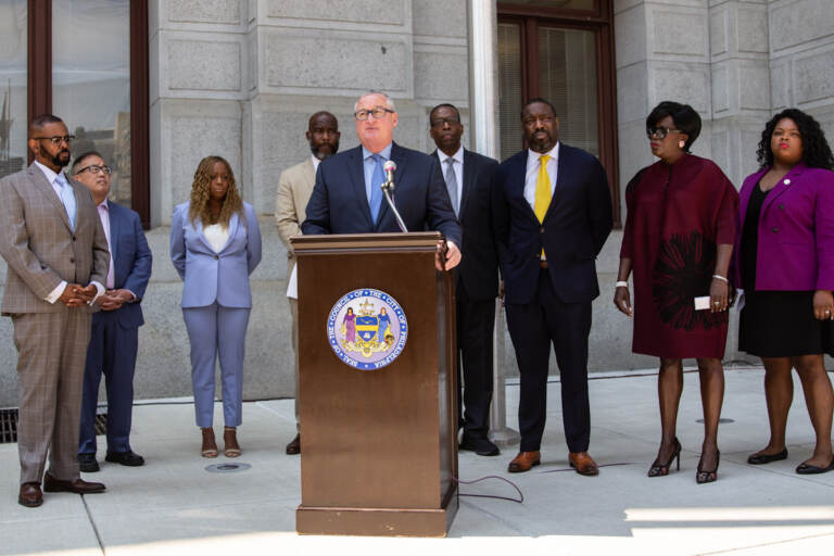 Jim Kenney speaks from a podium, with other elected officials behind him