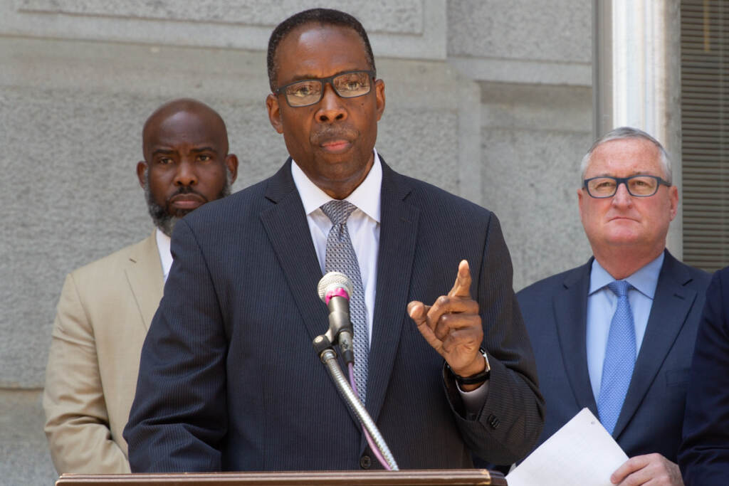 Darrell Clarke gestures while speaking from a podium, with other elected officials behind him