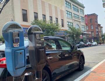 Parking meters are pictured in front of a car parked in Wilmington