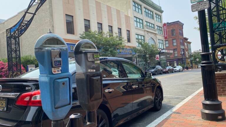 Parking meters are pictured in front of a car parked in Wilmington