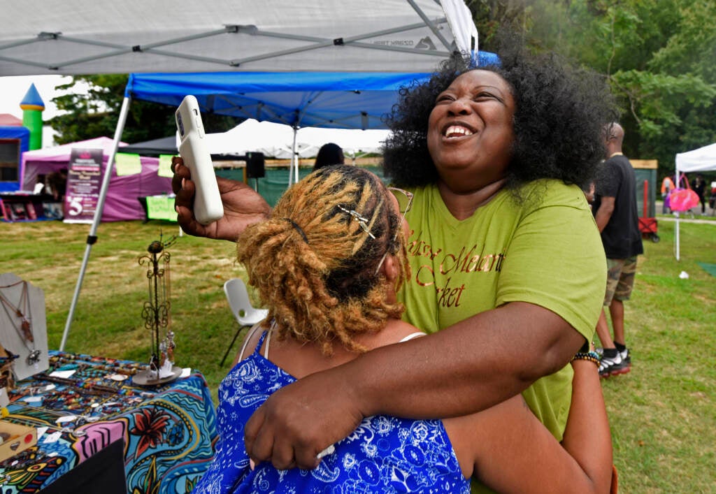 Two people embrace at grand opening of the Mask Melanin Market at its new Glassboro, NJ