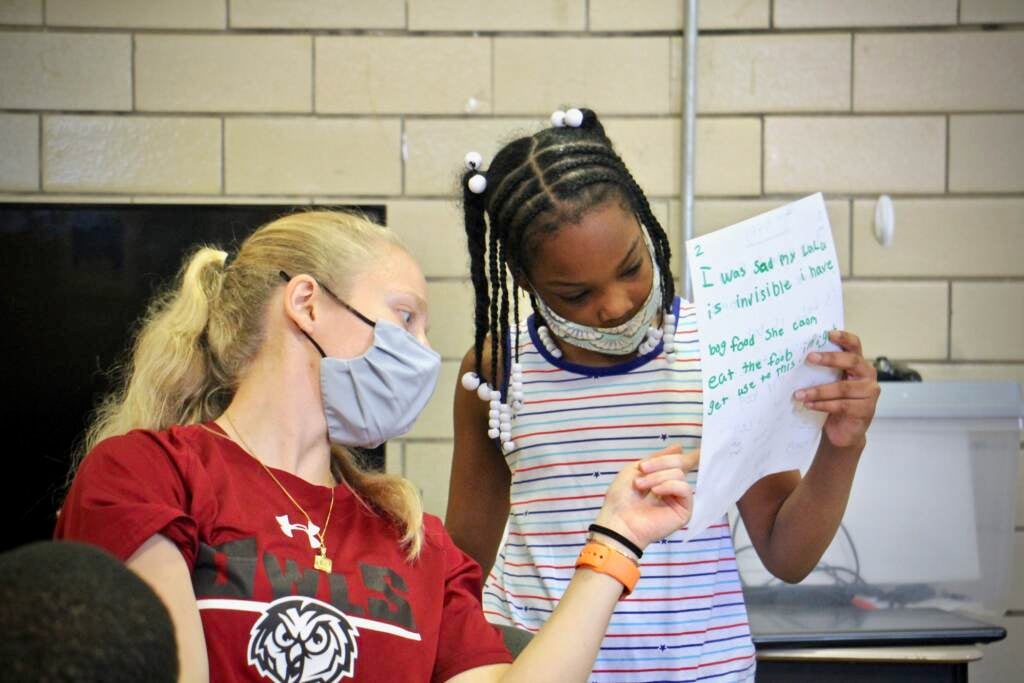 Instructor Emily Rankin helps 10-year-old Paris Counts with her writing