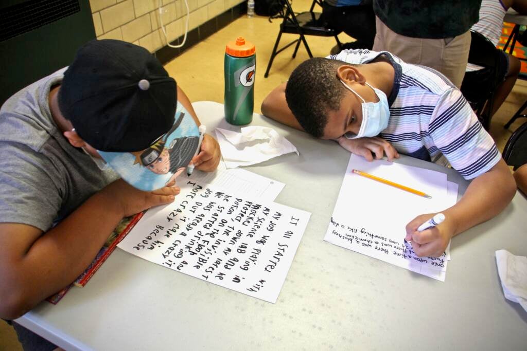 Omar Ayala and Major Counts write stories while wearing face masks