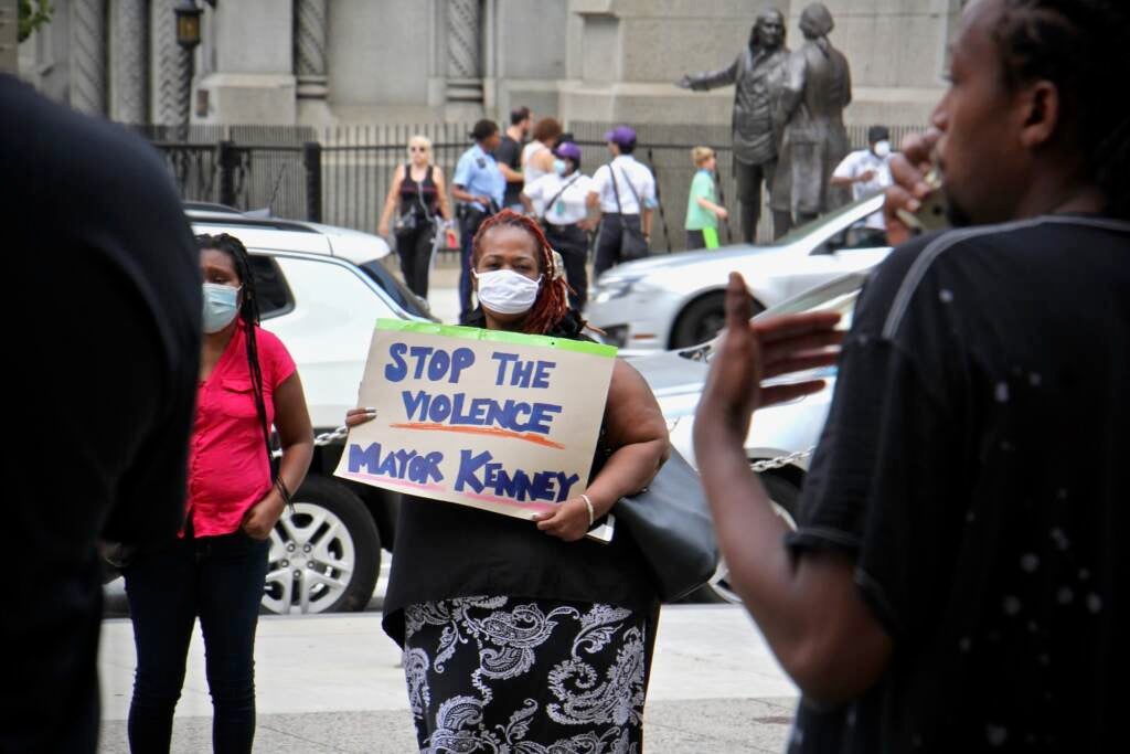 Christina Morton carries a sign outside City Hall during a rally