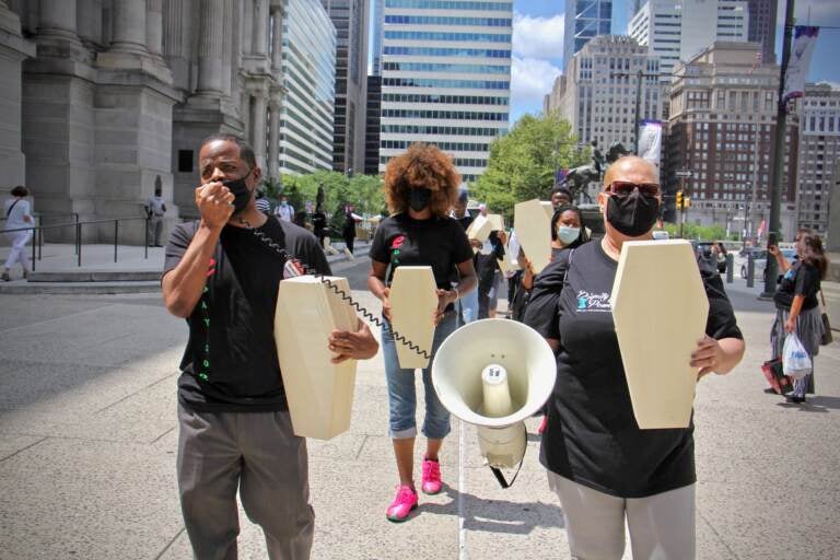Activists carry small coffins as they march around City Hall