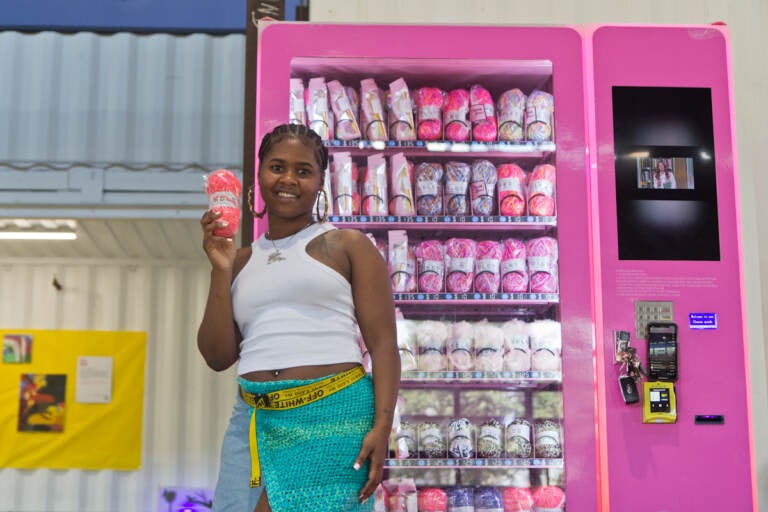 Emani Outterbridge holds up yarn in front of one of her vending machines