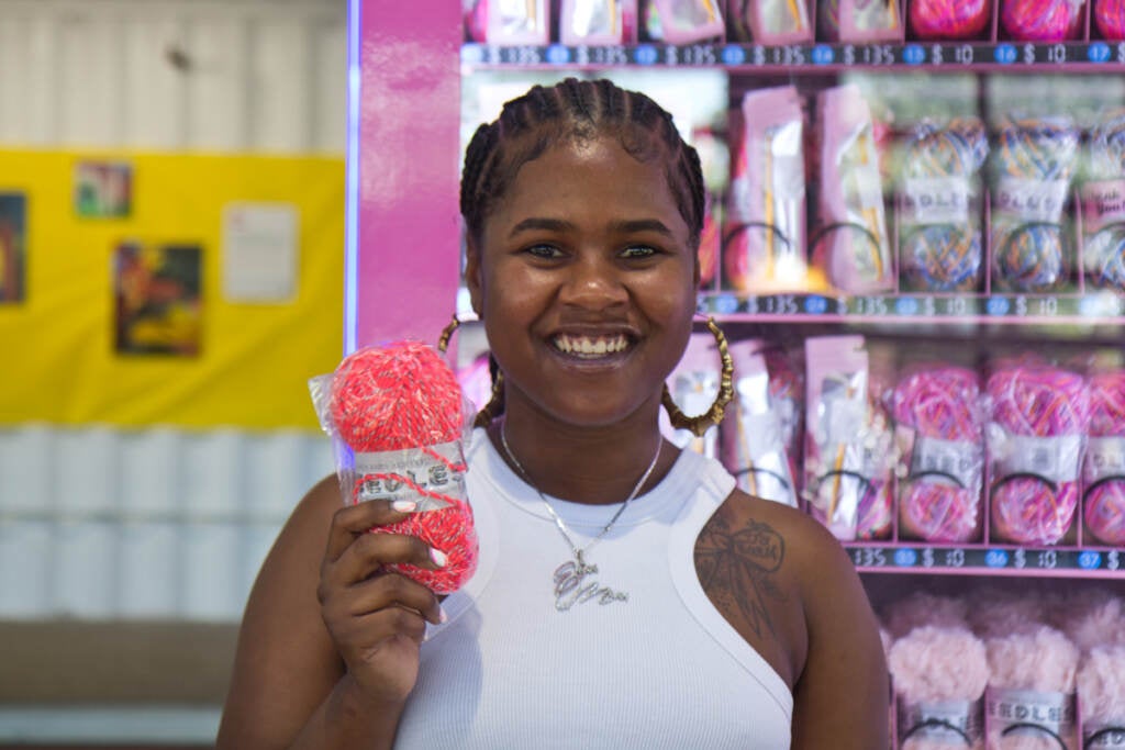 Emani Outterbridge holds up yarn in front of one of her vending machines