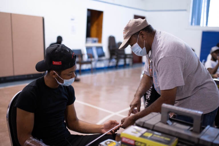 Saif Ashshaheed, 17, reviews reviews how to use a ruler with instructor Greg Palmer at the Dixon House community center in South Philadelphia on Tuesday, August 11, 2021. (Kriston Jae Bethel for WHYY)