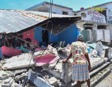 A woman stands in front of a destroyed home in the aftermath of an earthquake in Les Cayes, Haiti, Saturday, Aug. 14, 2021. A 7.2 magnitude earthquake struck Haiti on Saturday, with the epicenter about 125 kilometers ( 78 miles) west of the capital of Port-au-Prince, the US Geological Survey said. (AP Photo/Duples Plymouth)