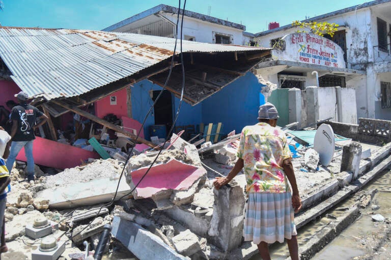 A woman stands in front of a destroyed home in the aftermath of an earthquake in Les Cayes, Haiti, Saturday, Aug. 14, 2021. A 7.2 magnitude earthquake struck Haiti on Saturday, with the epicenter about 125 kilometers ( 78 miles) west of the capital of Port-au-Prince, the US Geological Survey said. (AP Photo/Duples Plymouth)