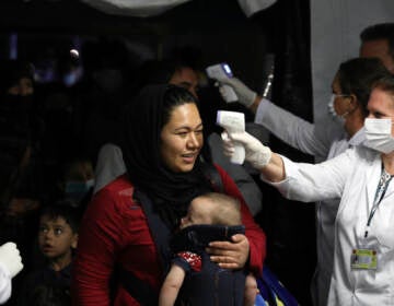 Health workers checks the temperature of evacuated citizens from Afghanistan upon their arrival at Tirana International Airport in Tirana, Albania, Friday, Aug. 27, 2021. A government decision has planned that the Afghans may stay at least a year during which they will proceed with their application for special visas before they move on to the US for final settlement. (AP Photo/Franc Zhurda)