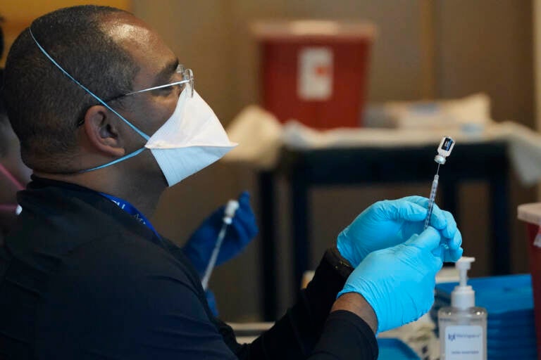 A health care worker fills a syringe with the COVID-19 vaccine.