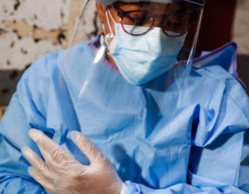 A closeup of a health worker wearing a face mask, scrubs, and gloves