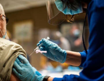 A person receives a COVID-19 vaccination from a health worker