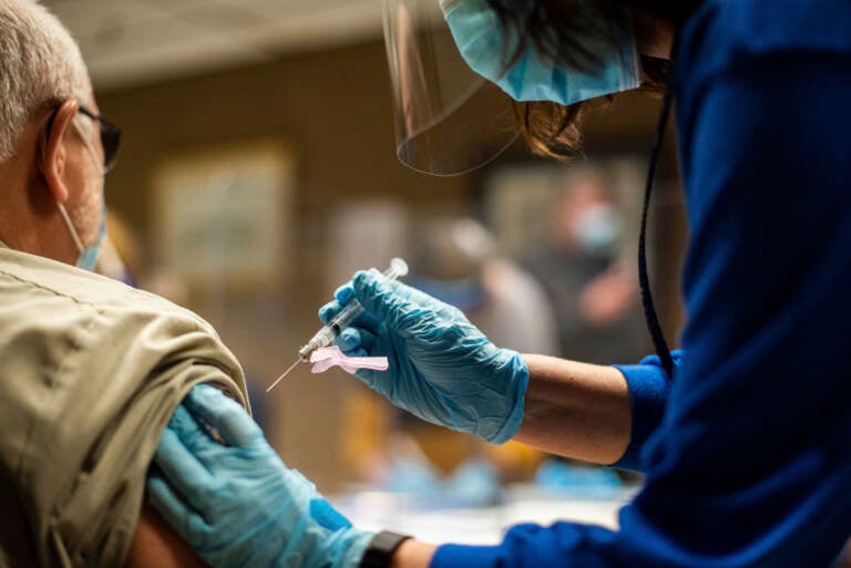 A person receives a COVID-19 vaccination from a health worker