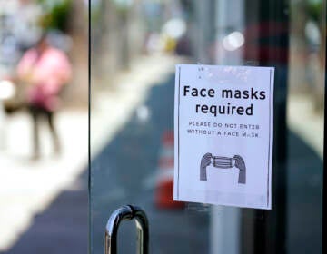 A sign advises shoppers to wear masks outside of a store