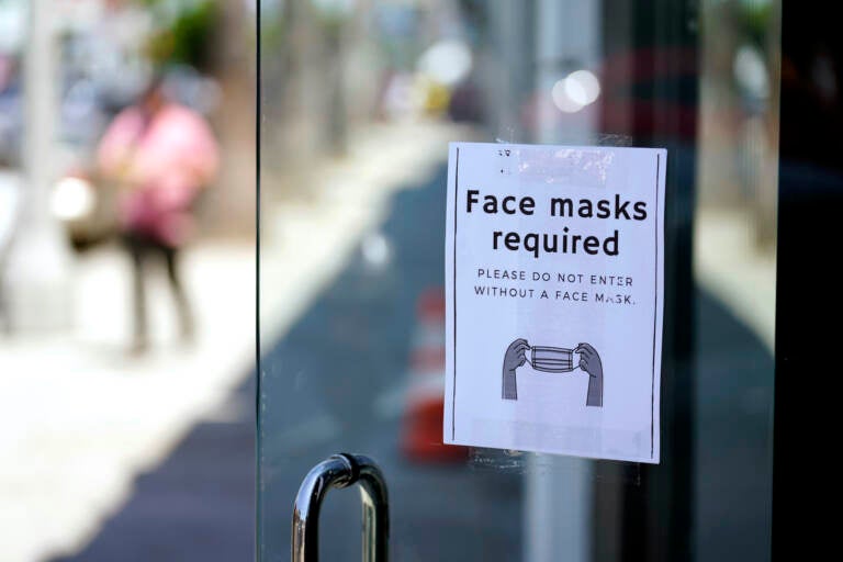 A sign advises shoppers to wear masks outside of a store