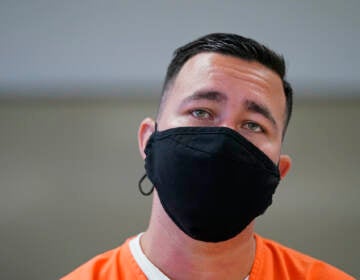 Alexander Martinez wears a face mask and detainee scrubs