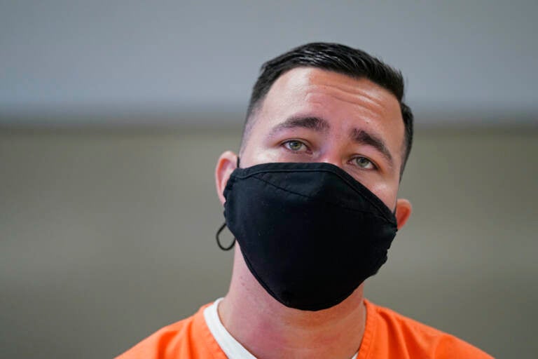 Alexander Martinez wears a face mask and detainee scrubs