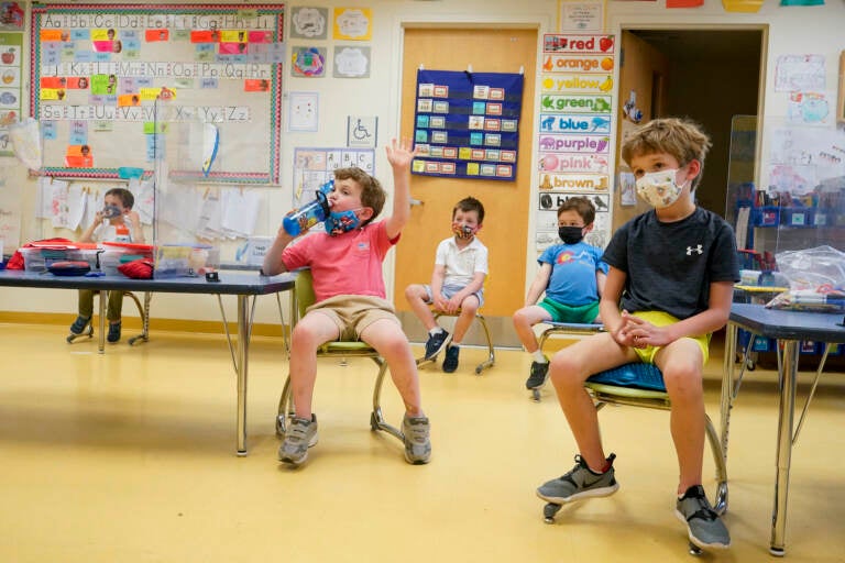 Kindergarteners wear face masks while sitting in a classroom