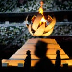 Volunteers stand as International Olympic Committee's President Thomas Bach gives a speech during the closing ceremony in the Olympic Stadium