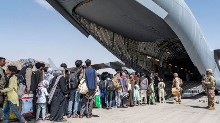 U.S. Airmen and Marines guide Afghan evacuees aboard a U.S. Air Force C-17 Globemaster III at Hamid Karzai International Airport in Kabul