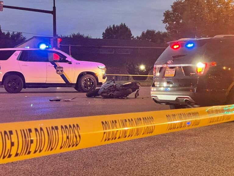 A motorcycle is pictured beside police vehicles and crime scene tape