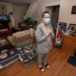 Stacey Horrocks stands inside her home wearing a face mask