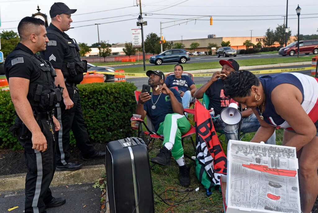 amden activist Gary Frazier (center) and other protesters eat pizza and chat with Deptford police officers