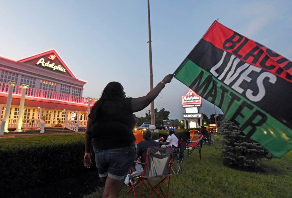 Clarkiya Wilson waves a Black Lives Matter flag outside Adelphia restaurant